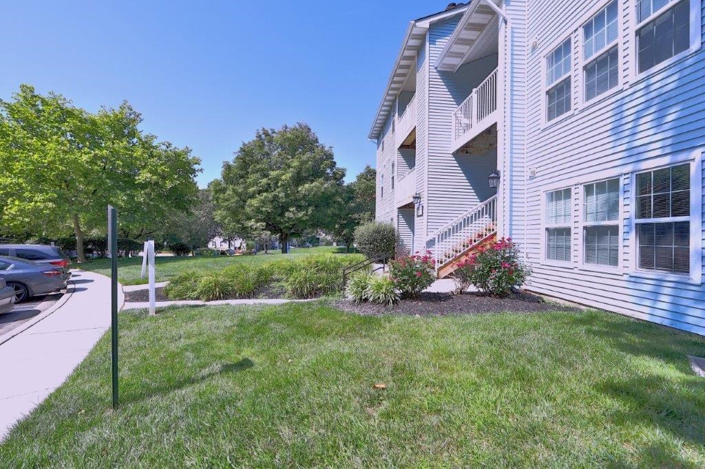the side of a house with a yard and a sidewalk