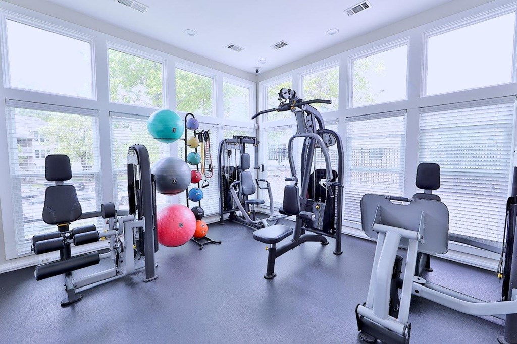 a gym with cardio equipment and windows in a building