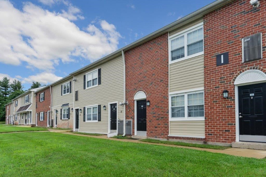 a brick apartment building with a green lawn