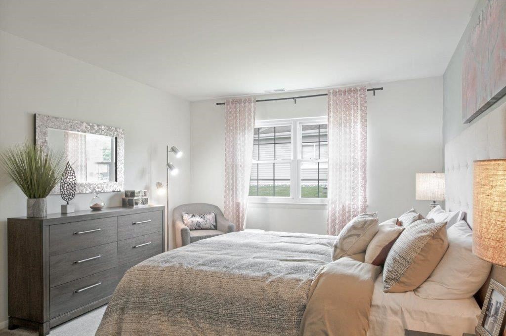 a bedroom with a bed and a dresser and a window