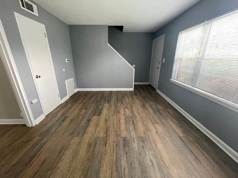 a renovated living room with wood flooring and a large window