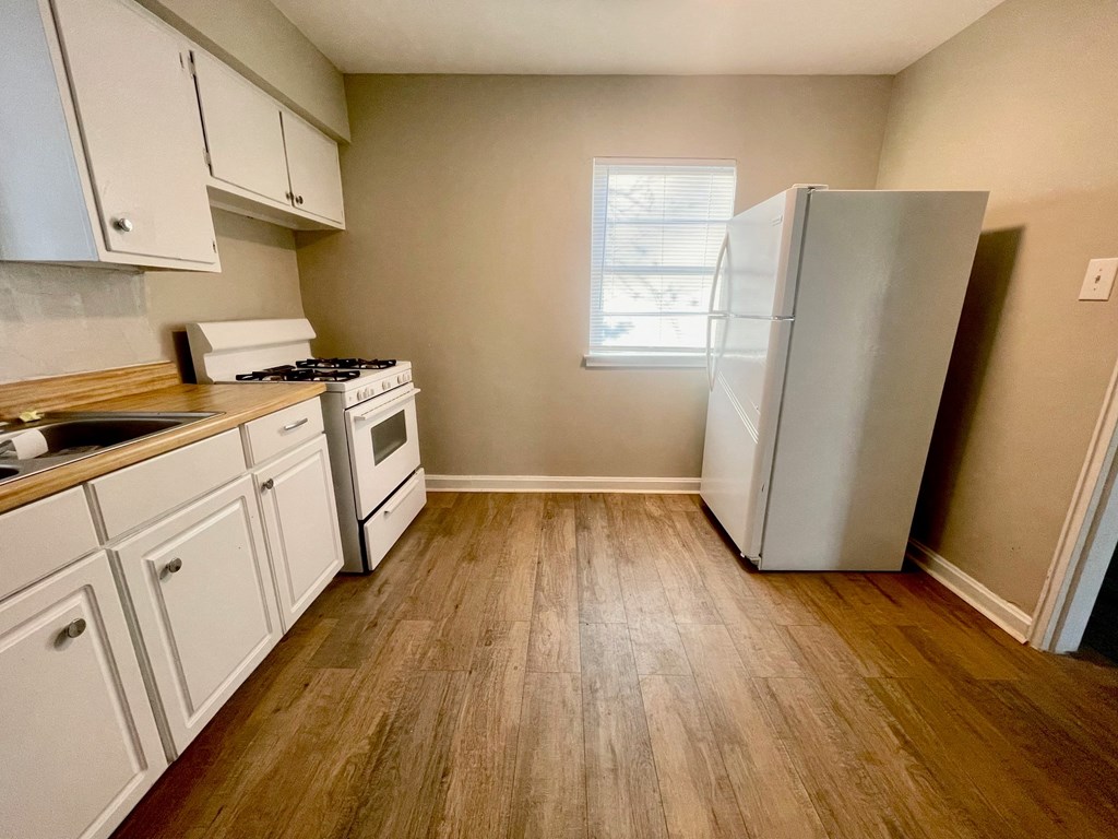 an empty kitchen with white cabinets and a refrigerator