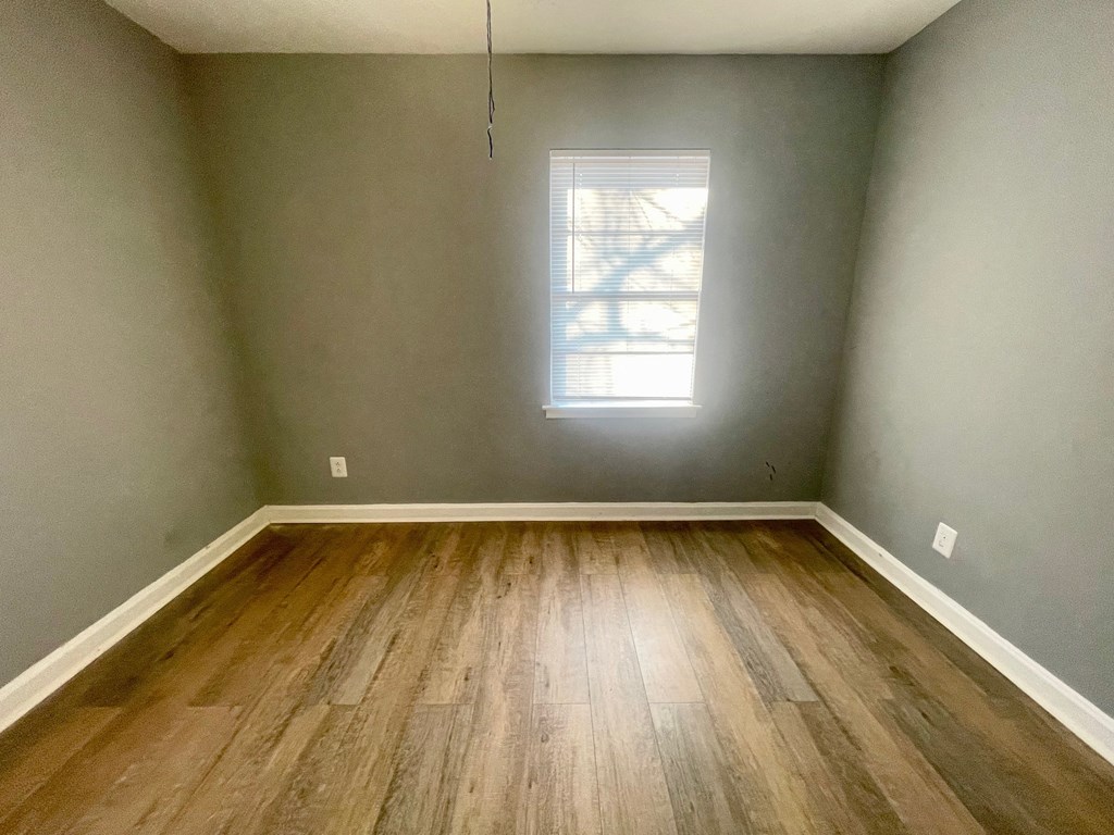 an empty room with wood floors and a window