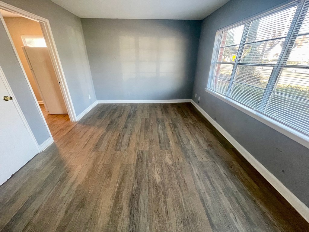 an empty living room with wood floors and a window