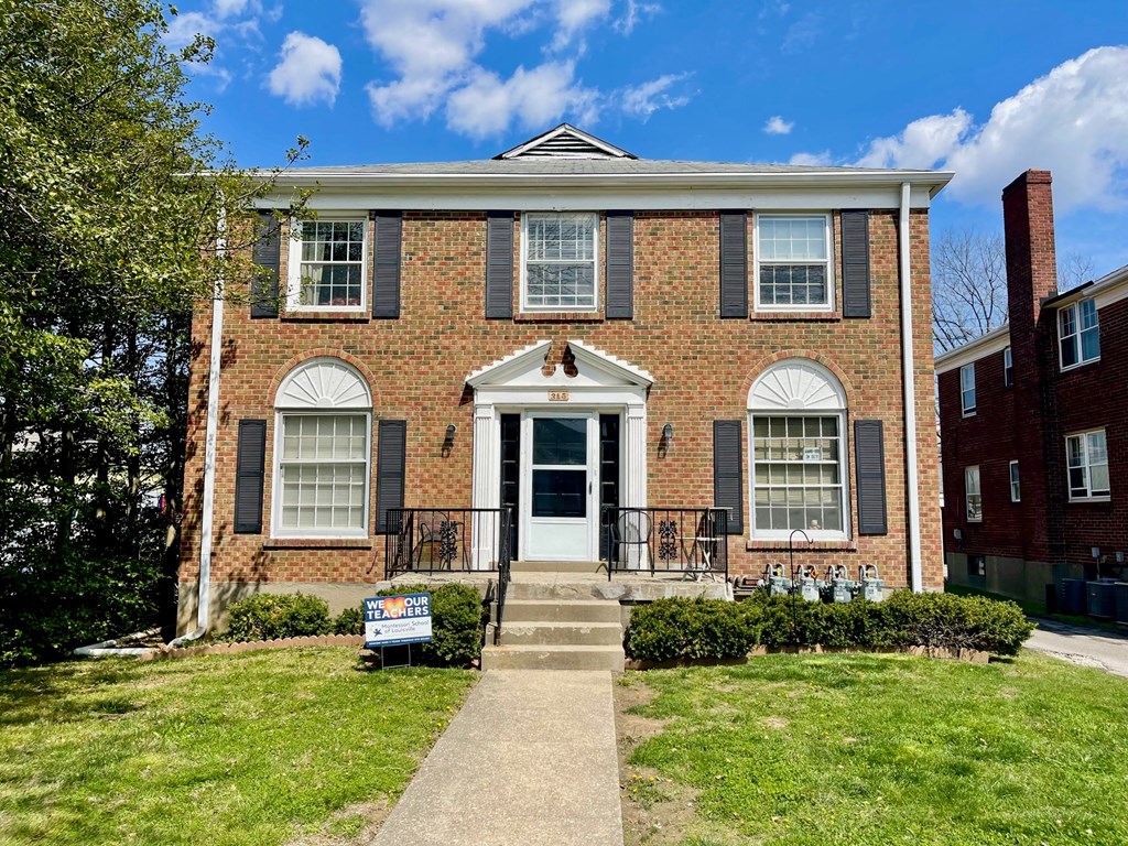 A red brick house with a white door and black shutters.