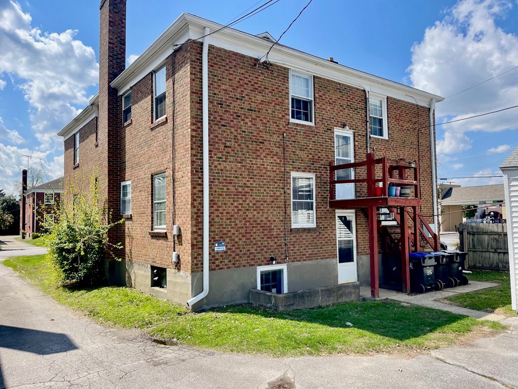 A red brick house with a white window and a red door.