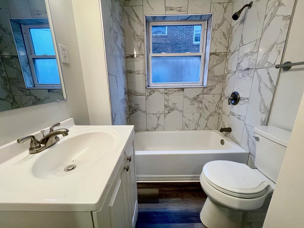 A white sink and toilet in a bathroom with a marble wall.