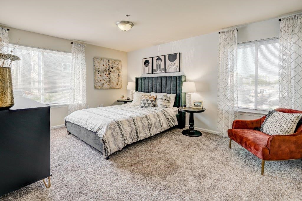 a bedroom with a bed and a chair and windows