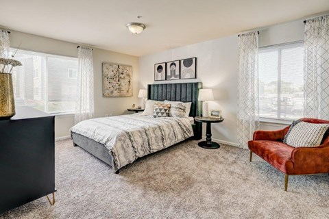 a bedroom with a bed and a chair and windows