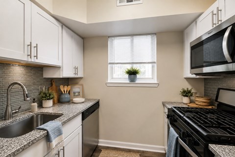 A kitchen with a black stove top oven and a black microwave above it.