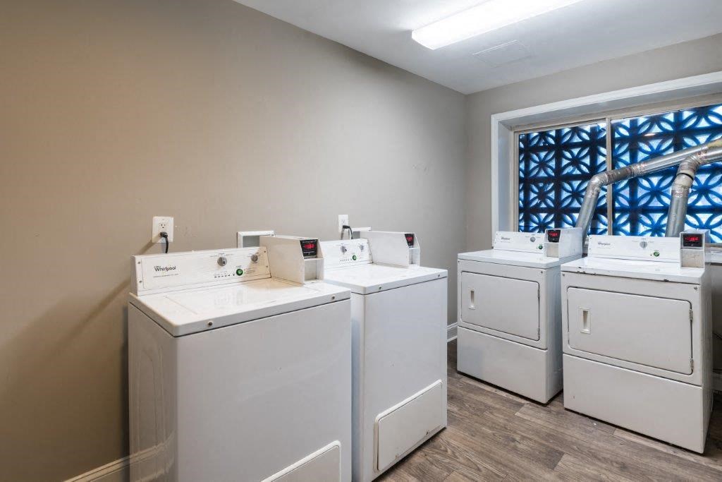 a row of washers and dryers in a laundry room with four washes
