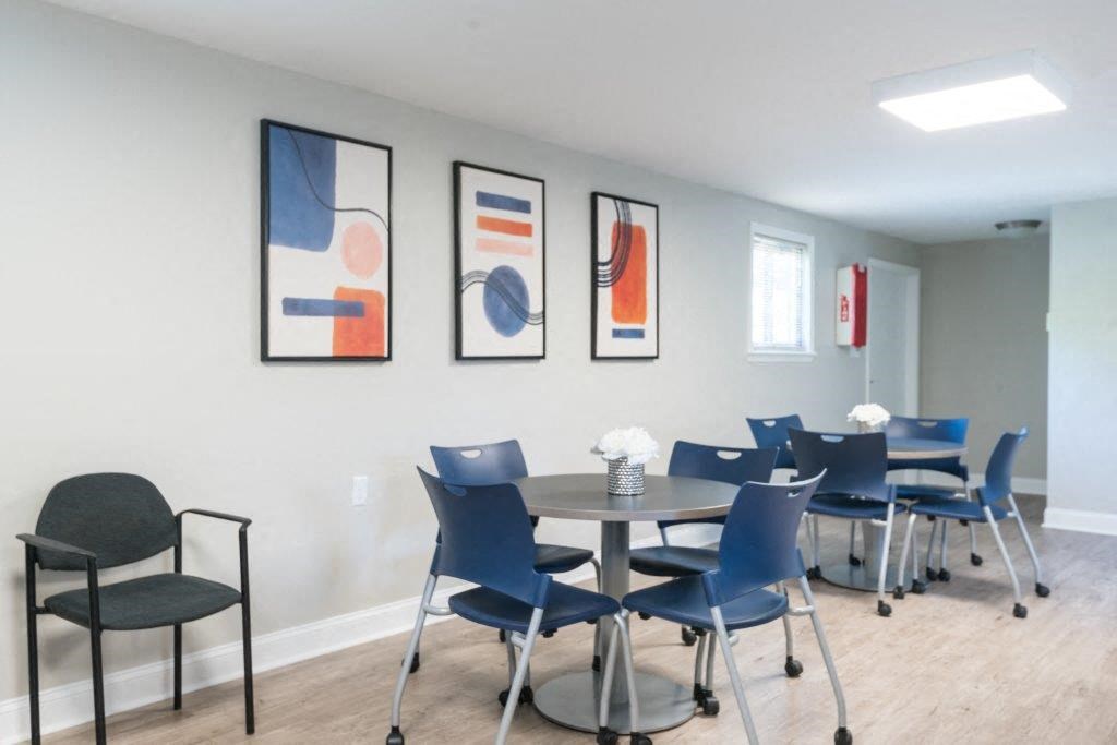a dining room table with blue chairs and paintings on the wall