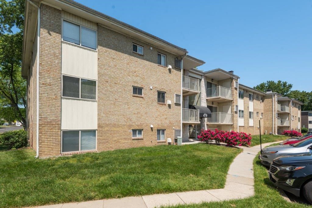 a brick apartment building with a sidewalk and grass
