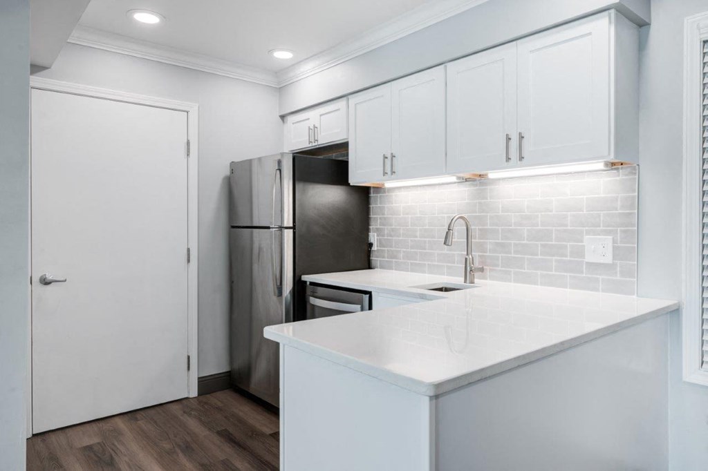 a kitchen with white cabinets and a stainless steel refrigerator