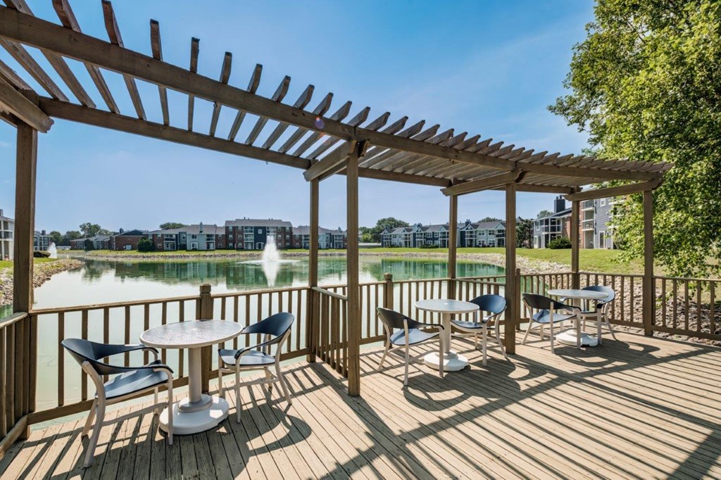 a covered patio with tables and chairs overlooking a lake