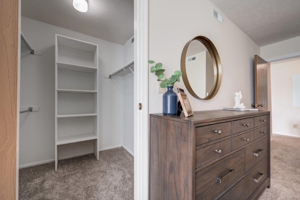 a closet in a bedroom with a mirror and a dresser