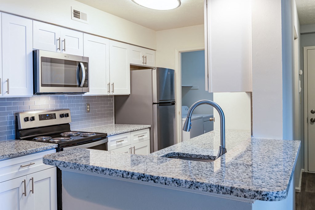 a kitchen with granite counter tops and white cabinets