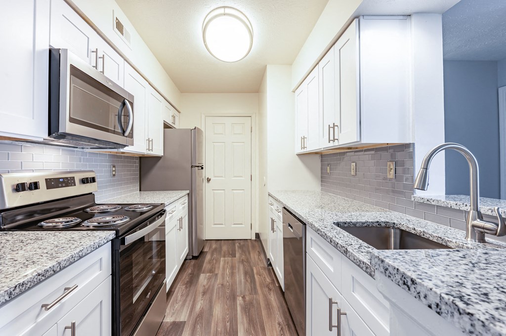a kitchen with marble counter tops and white cabinets