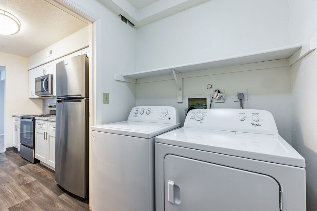 a washer and dryer in a laundry room with a stainless steel refrigerator