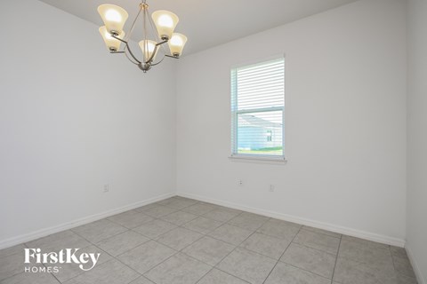 the living room of a home with a large window and a tiled floor