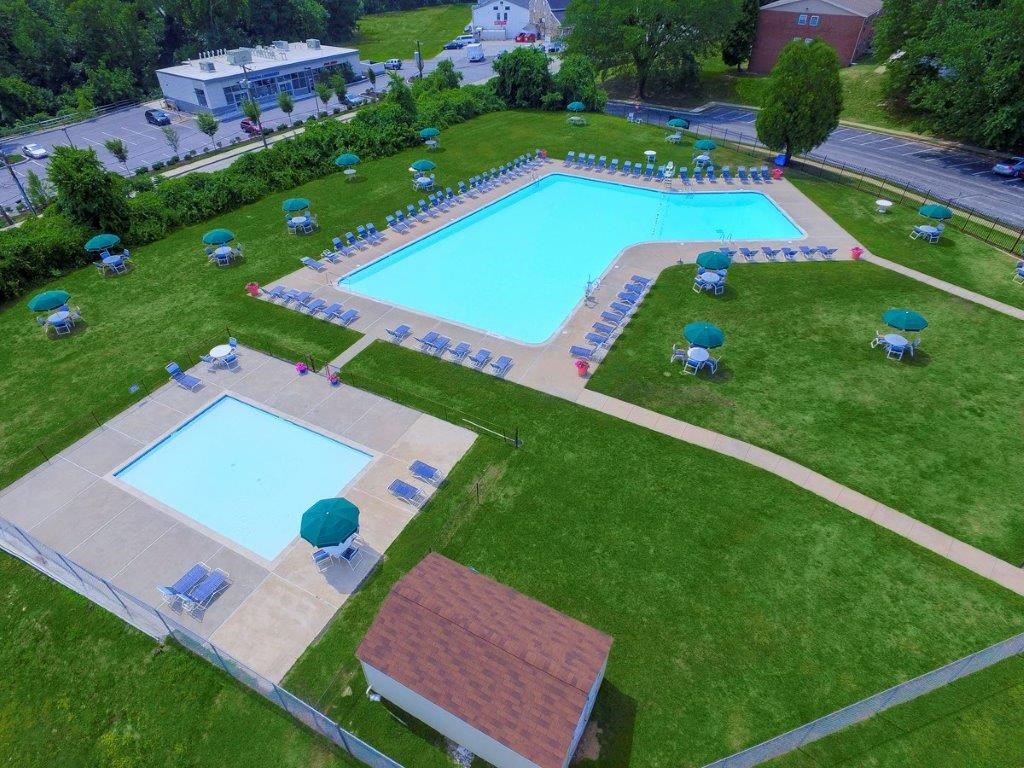 a resort style pool is shown in the grass with umbrellas