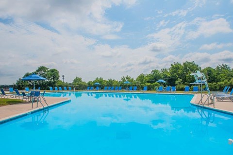 a large swimming pool with blue chairs and umbrellas