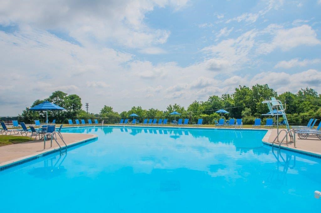 a large swimming pool with blue chairs and umbrellas