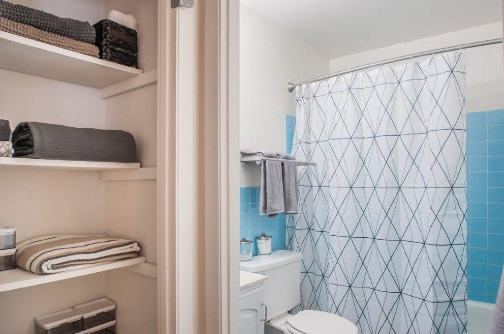 a bathroom with a shower curtain and a toilet and shelves