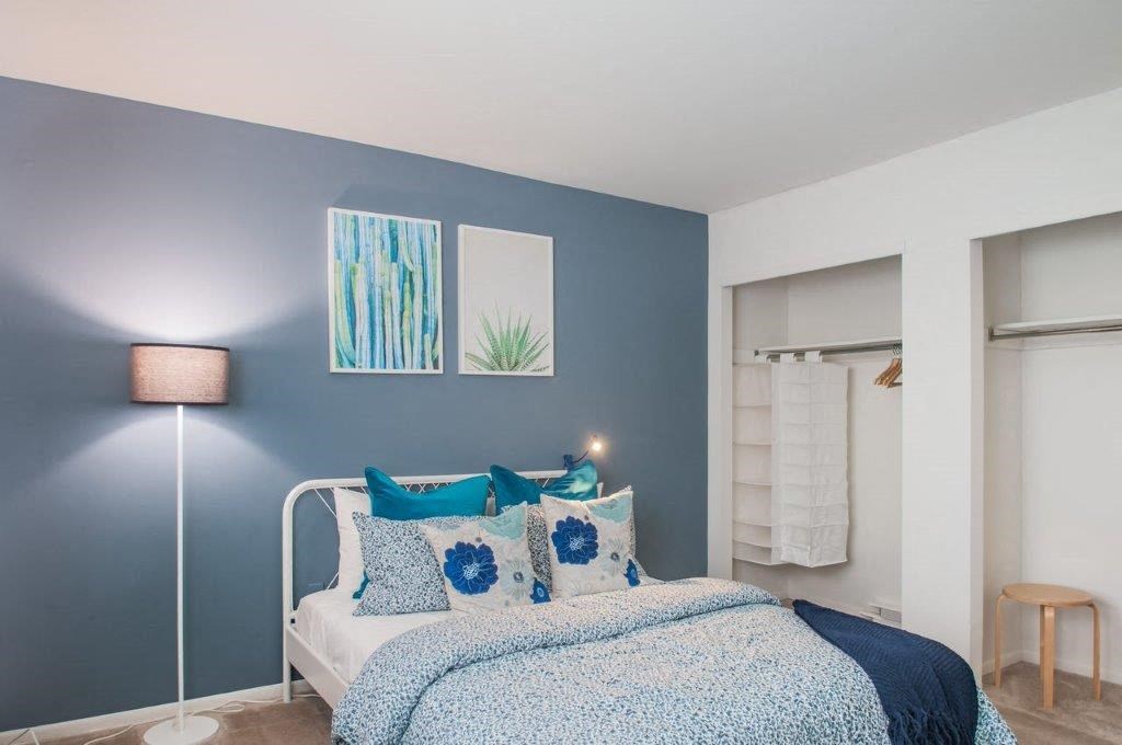 a bedroom with a bed and a blue wall and a closet
