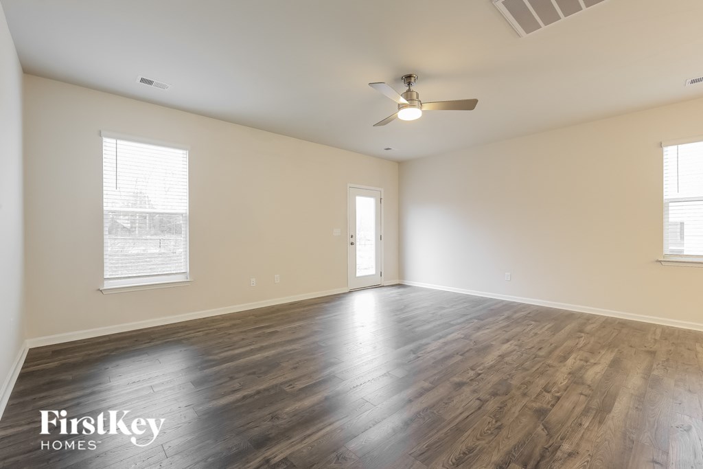 an empty living room with wood floors and a ceiling fan