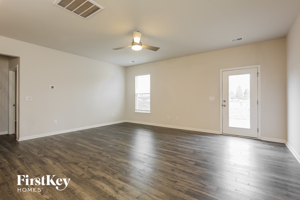 an empty living room with wood flooring and a ceiling fan