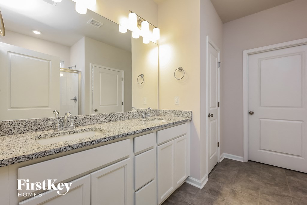 the master bathroom has a large vanity with dual sinks and a large mirror
