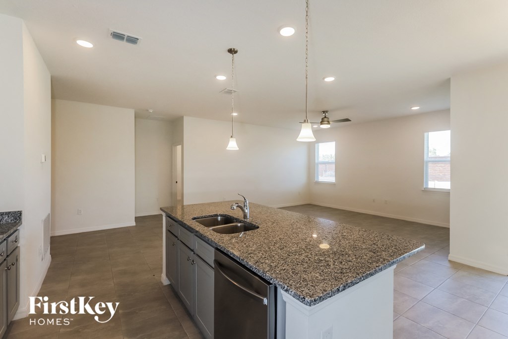 an empty kitchen with granite counter tops and a sink