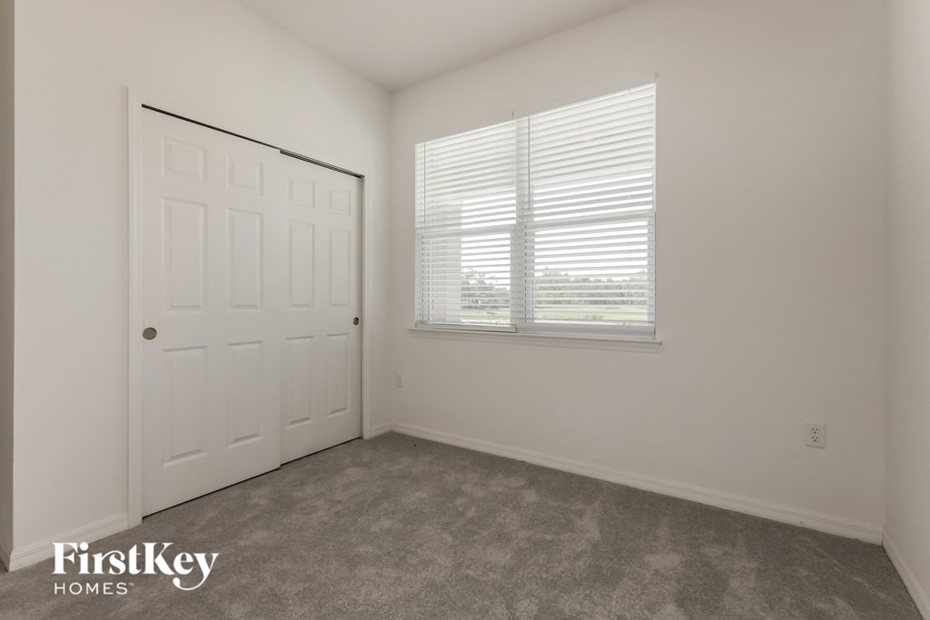 a bedroom with white walls and a white door and a window