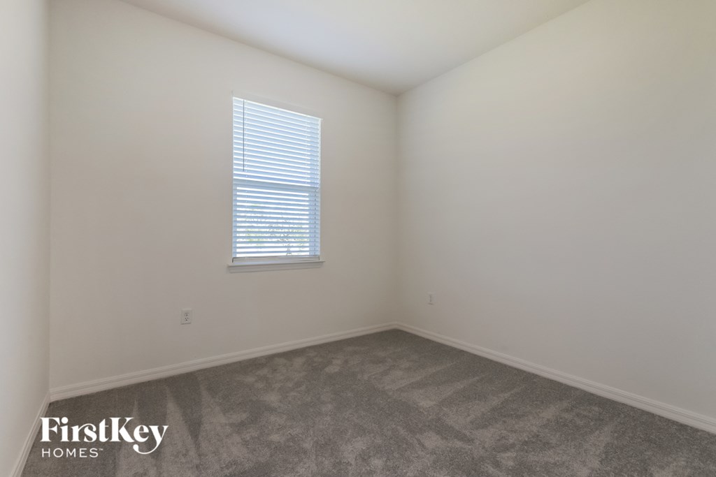 a bedroom with white walls and carpet and a window