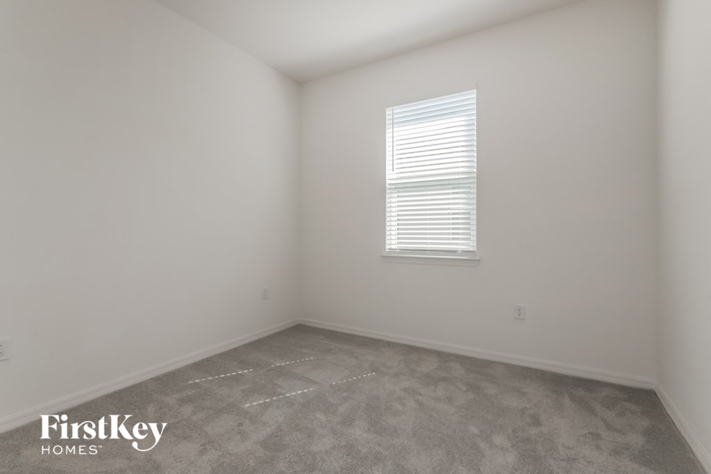 the living room of a home with white walls and a window