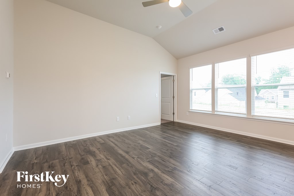 A spacious room with wooden flooring and a ceiling fan.