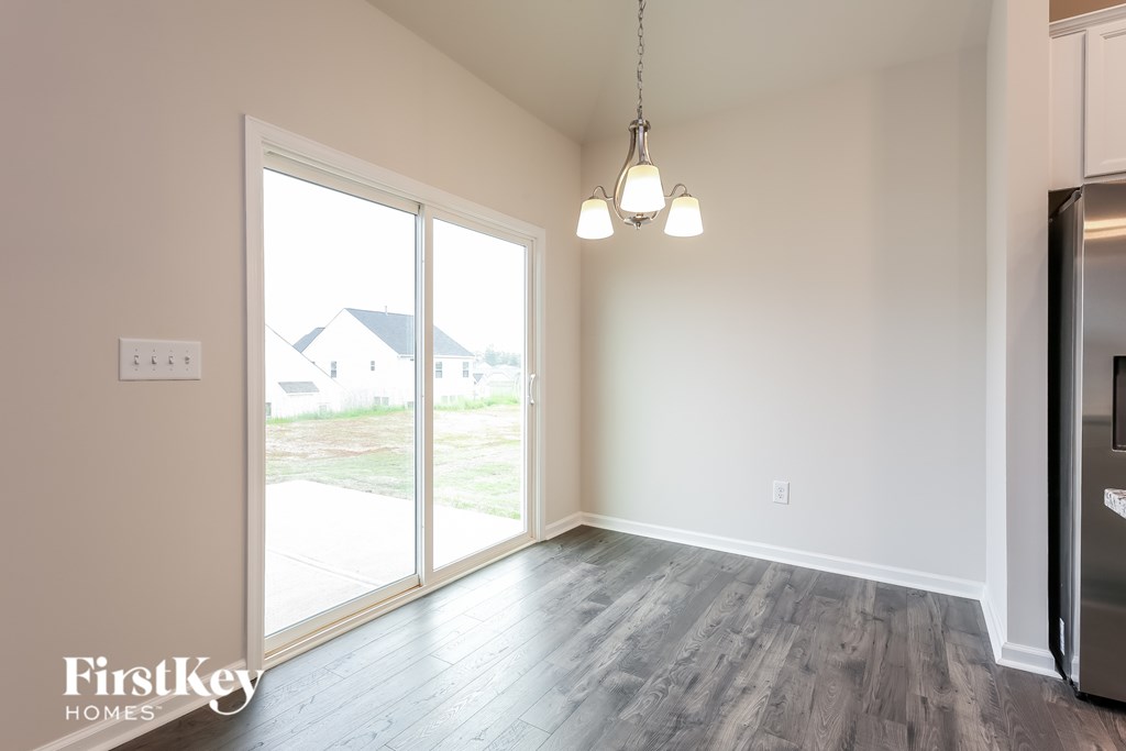 A room with a sliding glass door and a fridge on the right side.