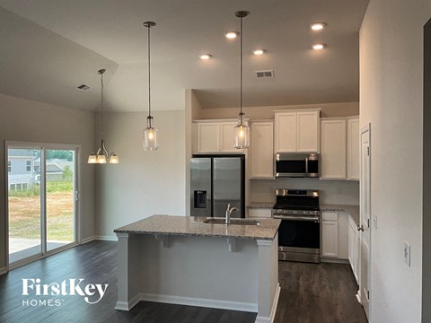 A kitchen with a granite countertop and a view of the backyard.