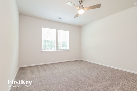 a spacious living room with carpet and a ceiling fan