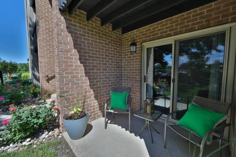 a patio with two chairs and a brick wall