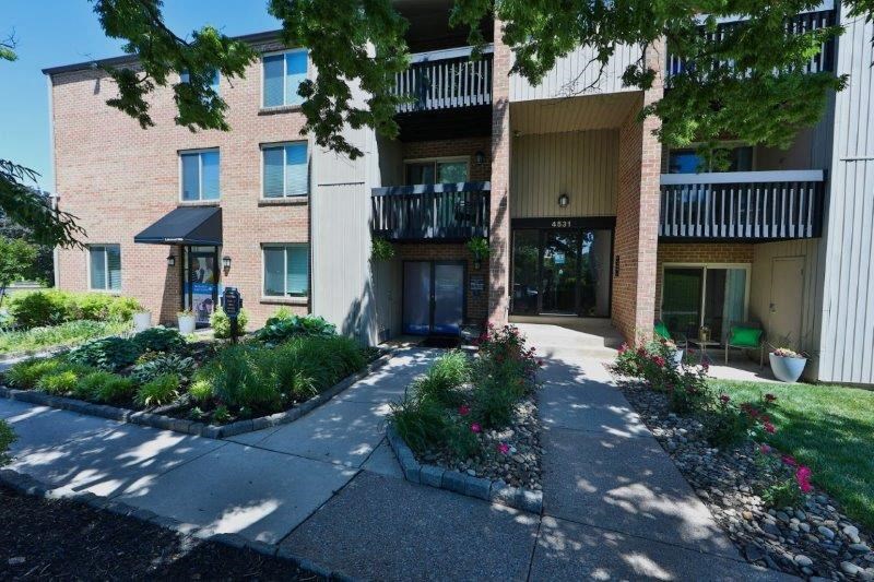 a sidewalk in front of a brick apartment building