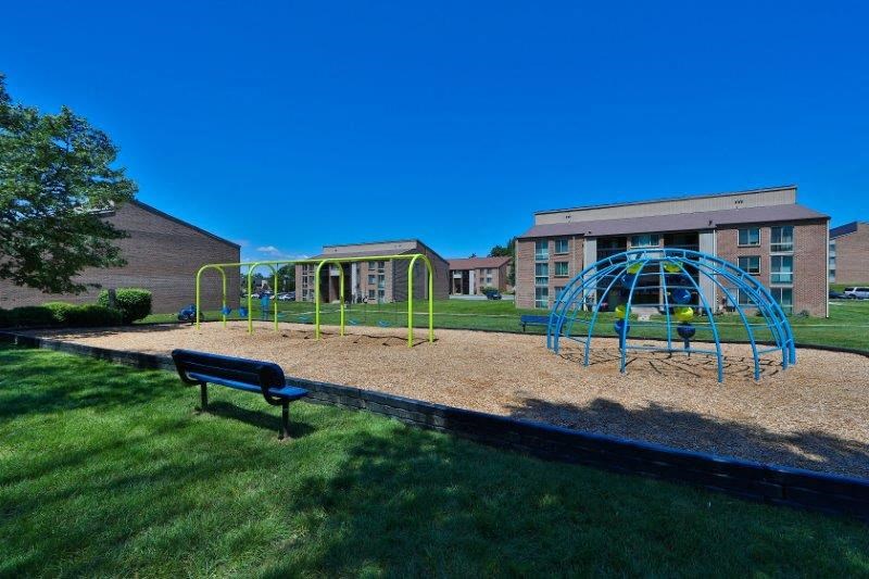 a playground with a bench in front of a building