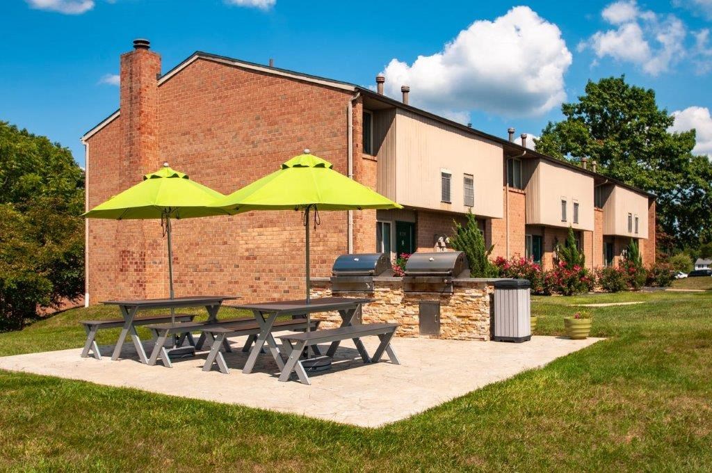 a patio with picnic tables and umbrellas in front of a house