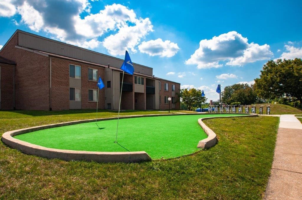 a putting green in front of a building with blue flags