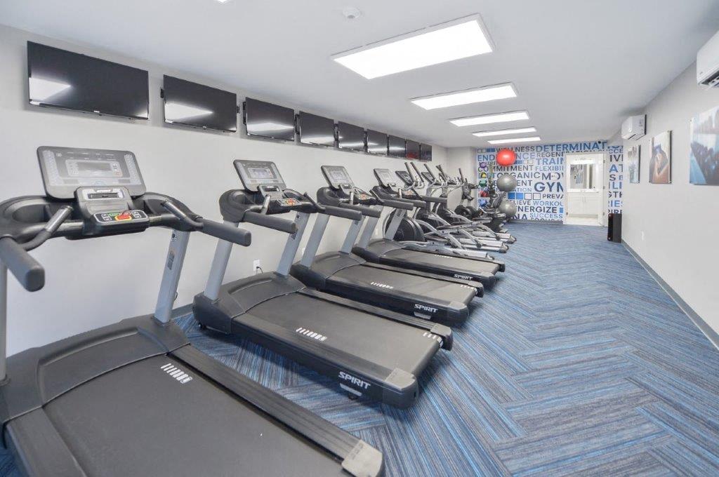 a gym with cardio equipment and a row of treadmills