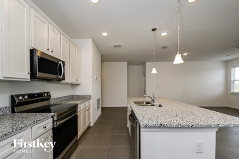 A kitchen with a granite countertop and a microwave above the stove.