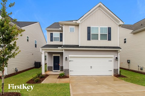 a beige and white house with a garage door and a lawn