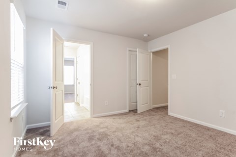 a master bedroom with a carpeted floor and doors to two closets