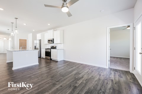 A spacious kitchen and living room with wooden floors and white walls.